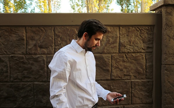 A Man in White Shirt Looking at His Smartphone