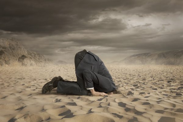A Person in Business Suit with Neck Deep in Sand